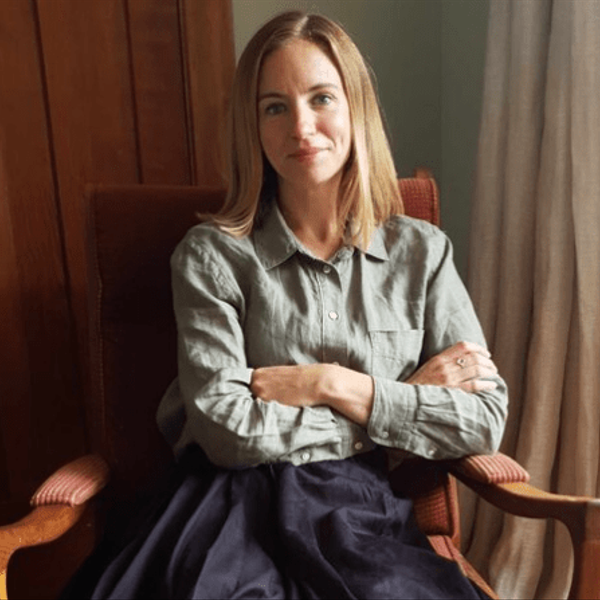 A woman sitting in a chair wearing a green blouse